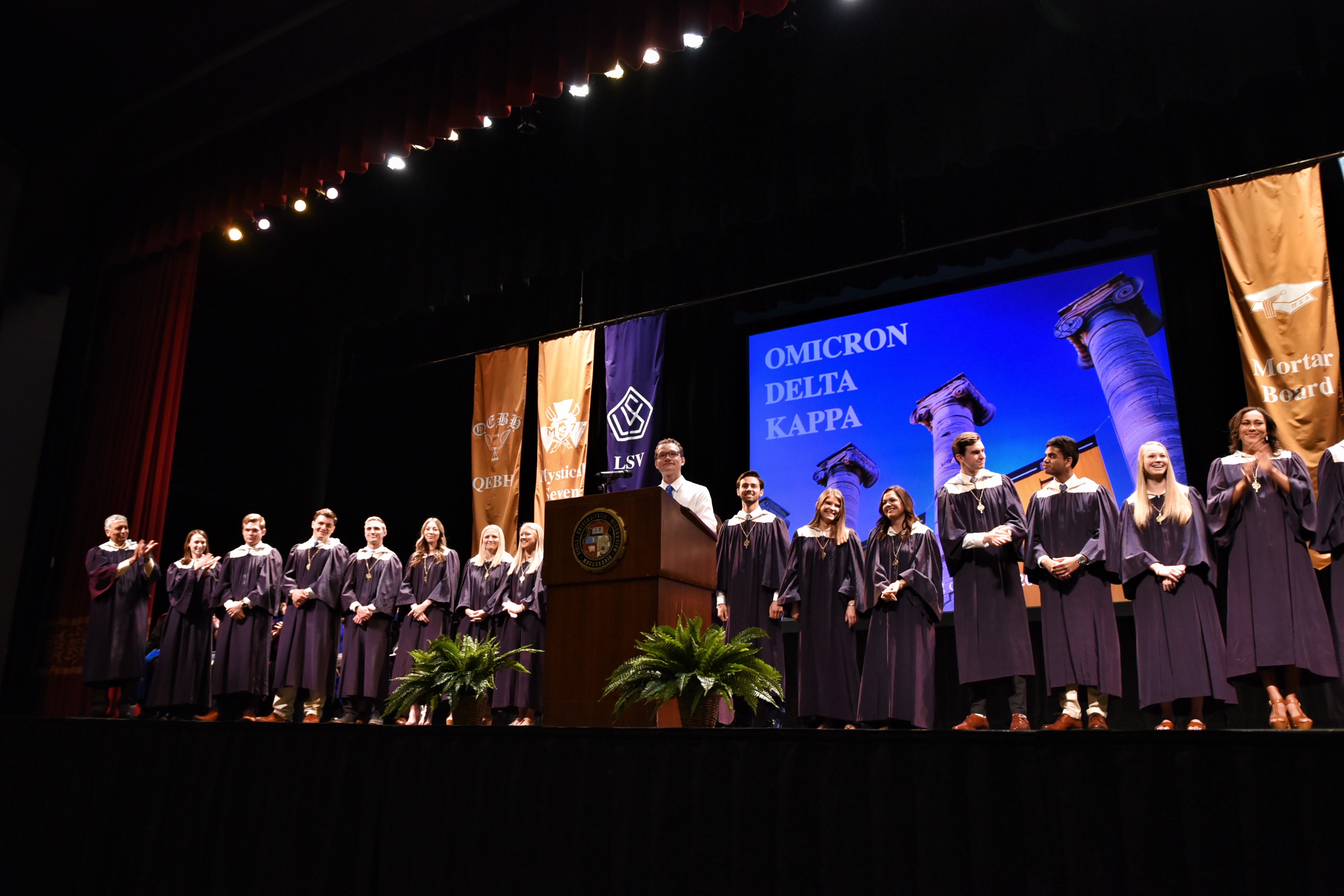 New members of Omicron Delta Kappa, wearing blue robes, are unveiled.