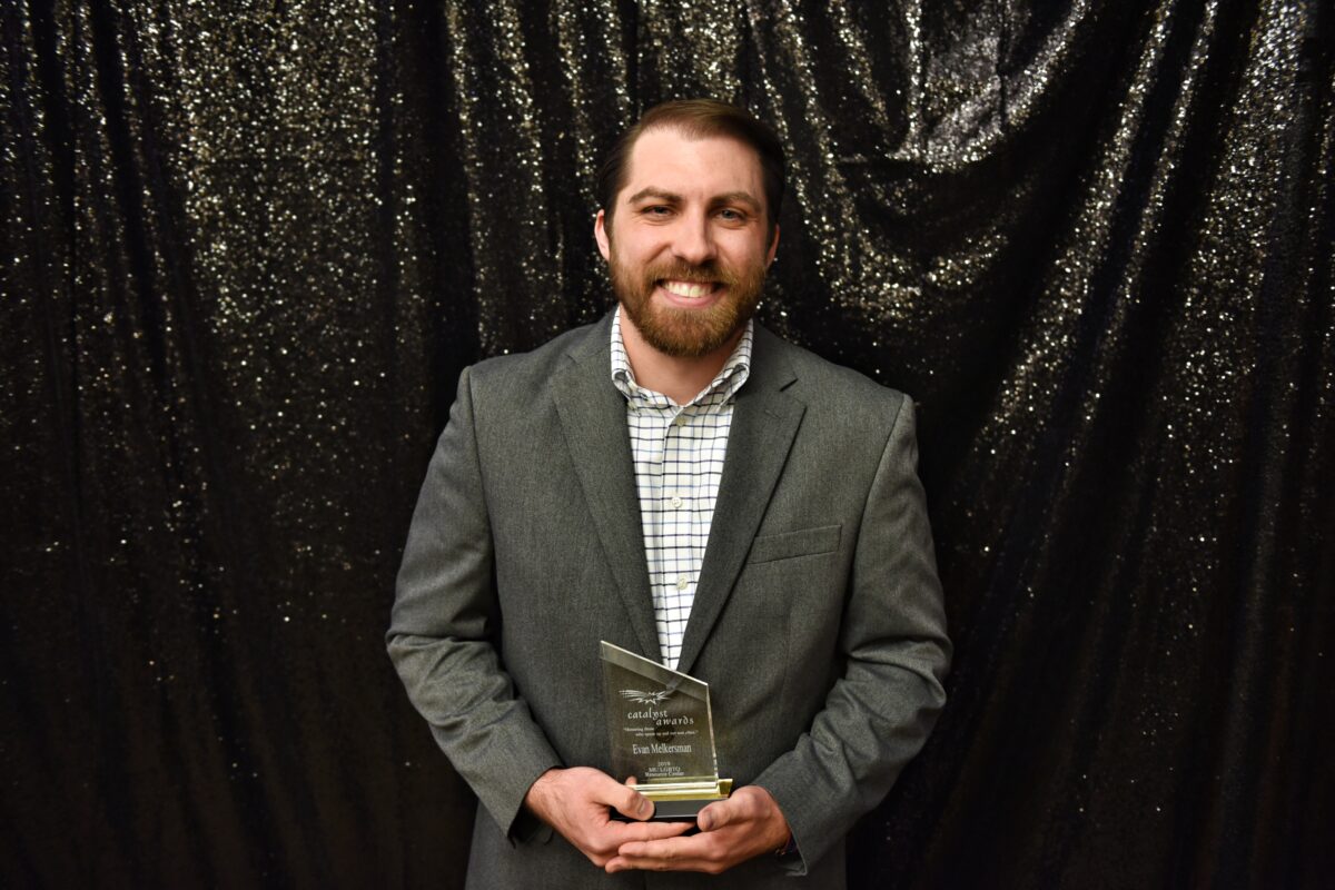 Man with a beard in a blazer holding his Catalyst Award.