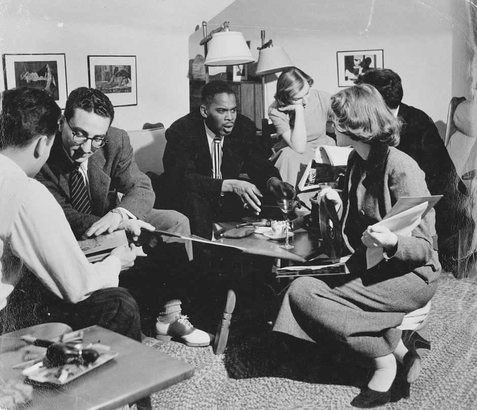 Black and white photo of Ridgel talks with students in a room during his time at MU.
