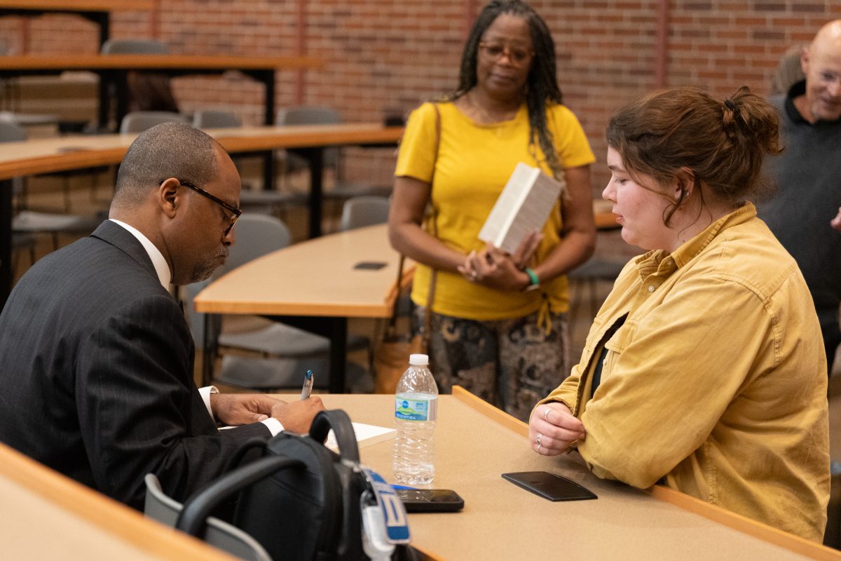 Dr. Jonathan "Jay" Augustine speaking with attendees during book signing.