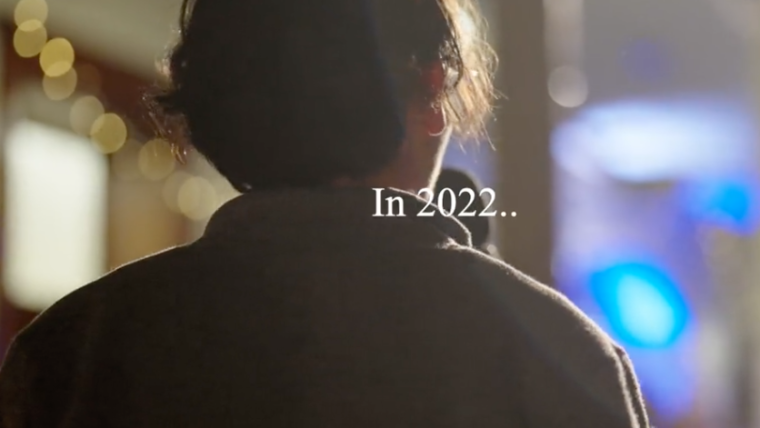 Opening screen of 2022 recap video. The back of student facing a stage in the distance with the words "In 2022..."
