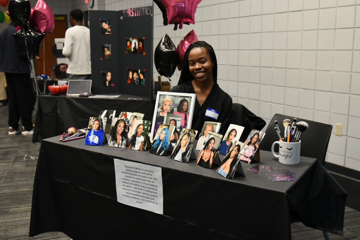 Dej Watson, owner of Beautybythabeast poses for photo in front of her table.