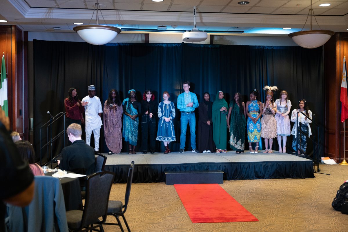 Student participants stand for a round of applause at the conclusion of the event in their traditional garments. 